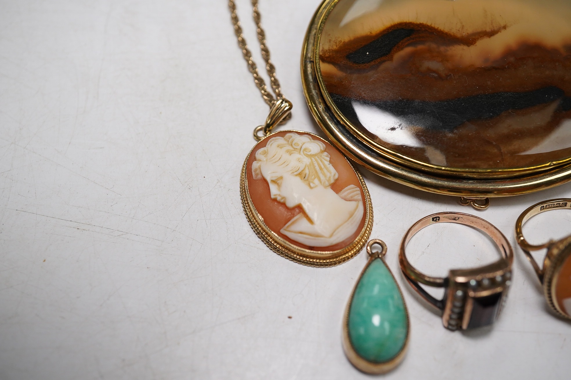 Three assorted 9ct gold rings, including cameo shell and sapphire and diamond half hoop, together with two pendants including 9ct mounted cameo shell on a 9ct chain and a yellow metal mounted agate brooch. Condition - po